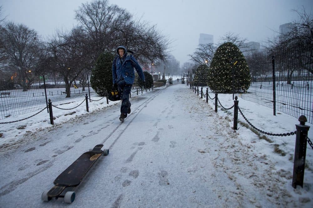 A skateboarder chases his runaway skateboard in the snow at the Boston Public Garden. (Jesse Costa/WBUR)