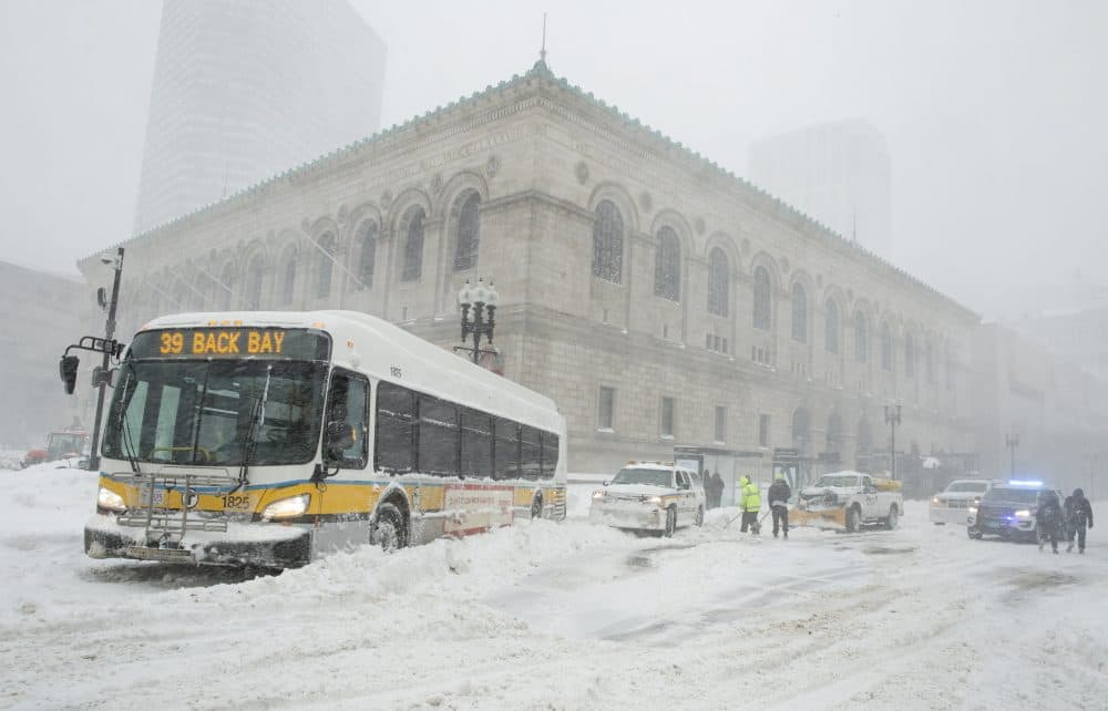 MBTA staff work to move a bus stuck across Boylston Street in front of the Boston Public Library. (Robin Lubbock/WBUR)