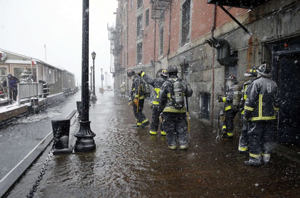 Boston firefighters work at the scene of flooding from Boston Harbor on Long Wharf in Boston. (Michael Dwyer/AP)