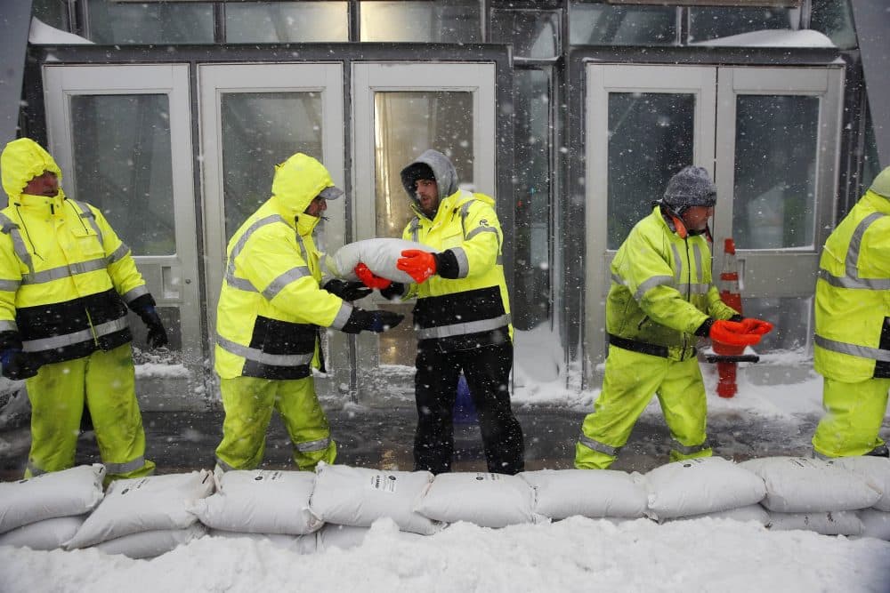 Workers place sand bags in front of Aquarium subway station to protect against flooding from Boston Harbor. (Michael Dwyer/AP)