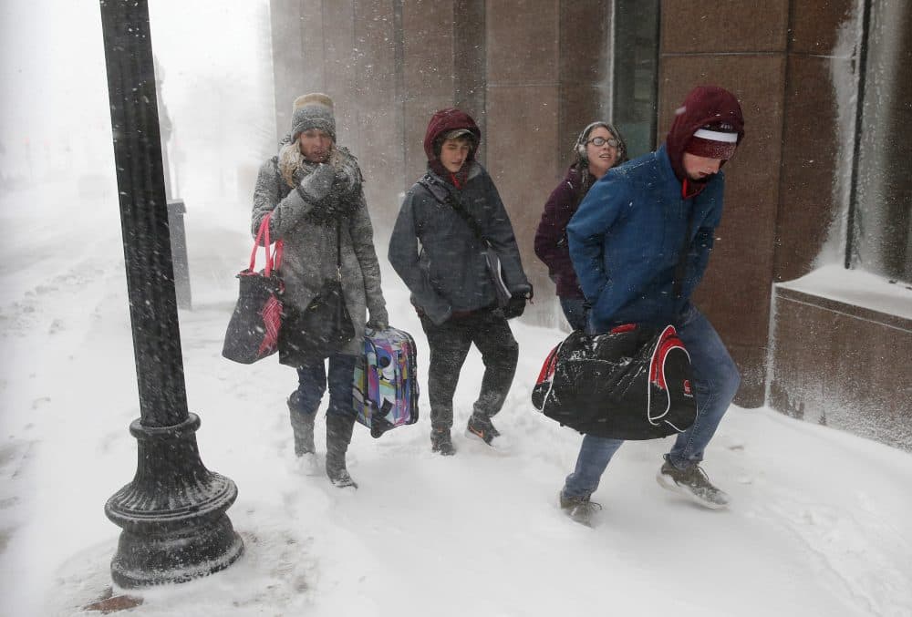 People with luggage walk through the snow in Boston. (Michael Dwyer/AP)