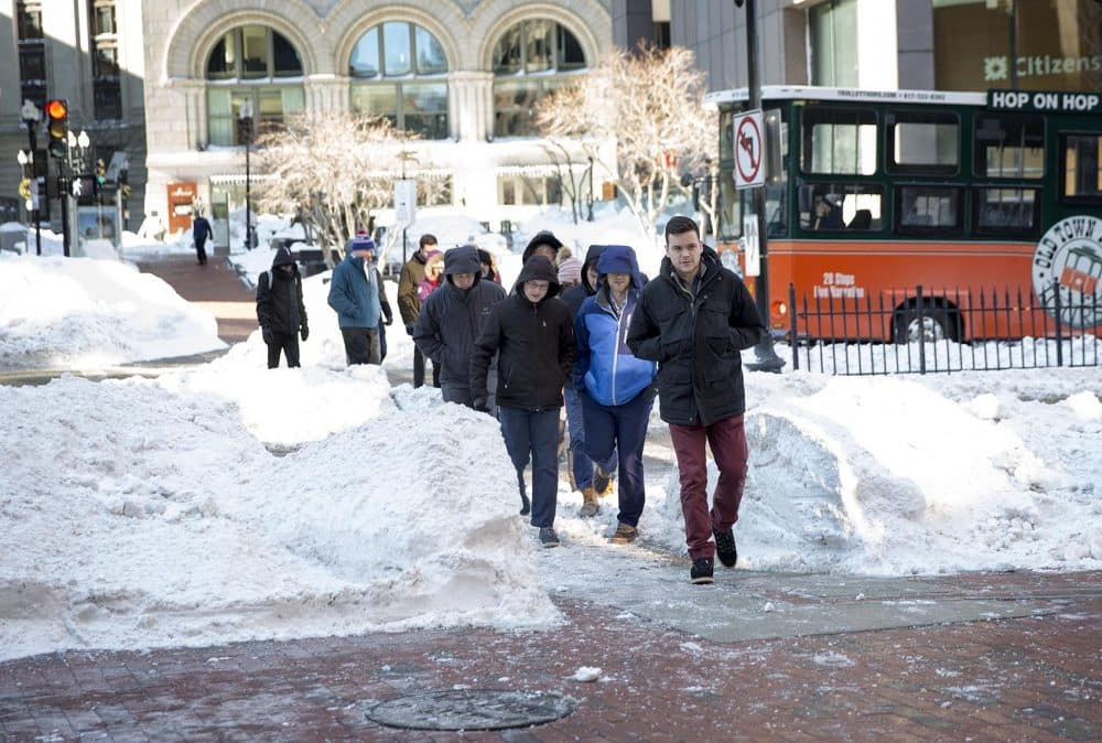 People navigate their way through snowbanks as they cross a street in downtown Boston. (Robin Lubbock/WBUR)