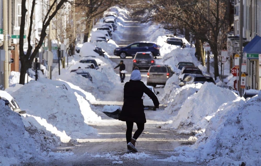 Mollie Lane carries a shovel-full of snow down the street to a pile while digging her car out in the South Boston neighborhood of Boston. (Charles Krupa/AP)