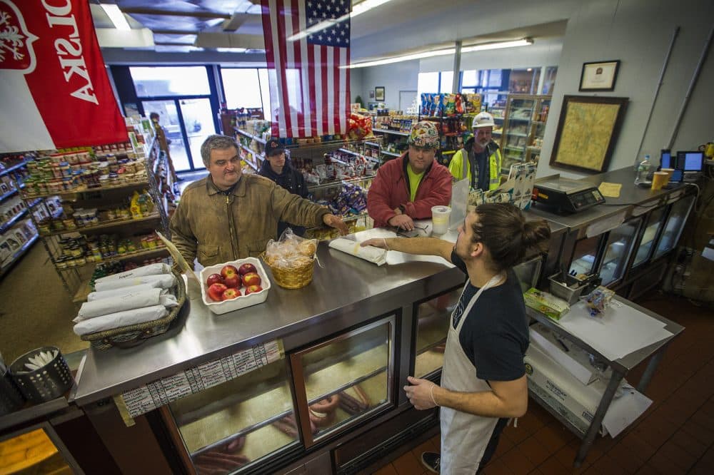 At the beginning of the morning rush, Jordan Hislop hands over a sandwich to a customer at DJ's European Market in Dorchester. (Jesse Costa/WBUR)