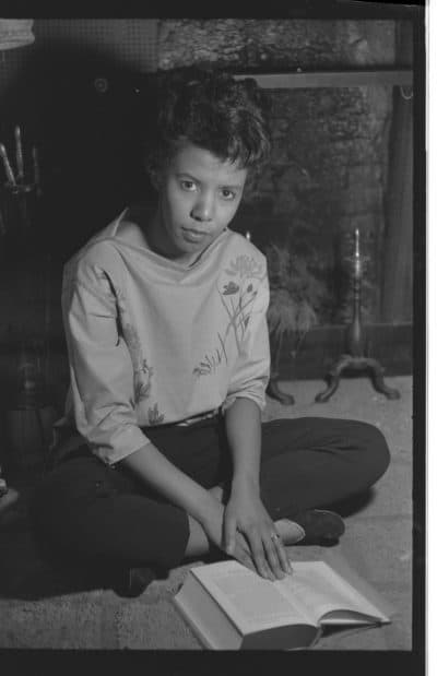 Lorraine Hansberry sitting on the floor of her home holding open a book. (Courtesy Gin Briggs/Lorraine Hansberry Properties Trust)