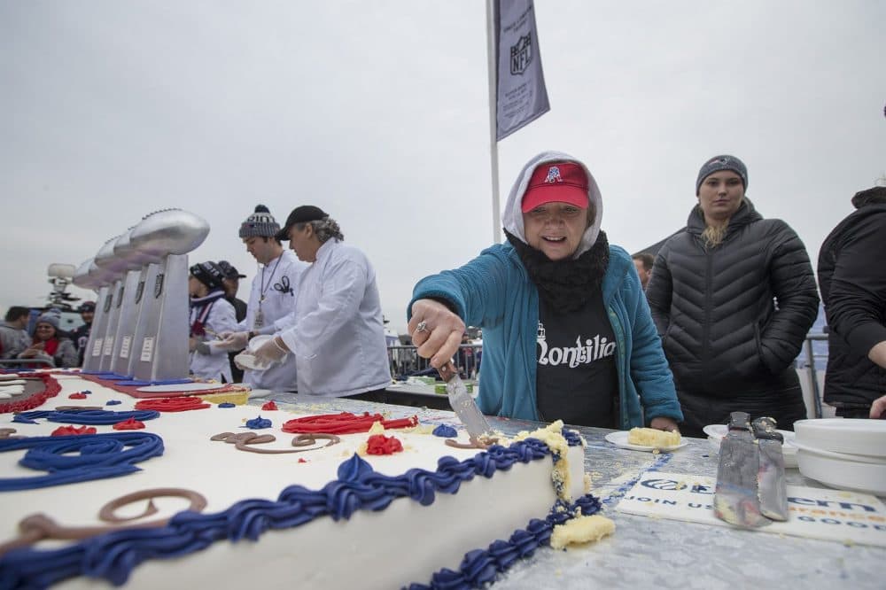 Volunteer Marie Luckdale cuts pieces of cake, which was handed out to fans at the rally. (Jesse Costa/WBUR)