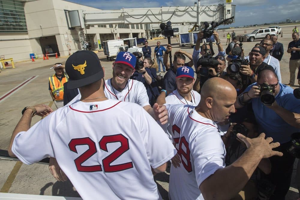 Shorty after landing in San Juan, Rick Porcello (22) and Alex Cora (28) are greeted by teammates Chris Sale, left, and Christian Vazquez. (Jesse Costa/WBUR)