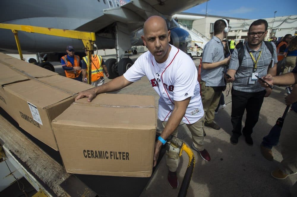 At the airport in Puerto Rico, Cora picks up a box of supplies. (Jesse Costa/WBUR)