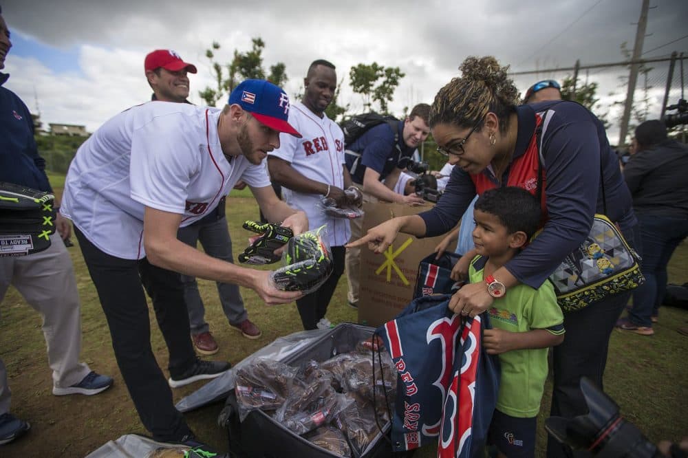 Pitcher Chris Sale offers a baseball glove to a young boy in Caguas. (Jesse Costa/WBUR)