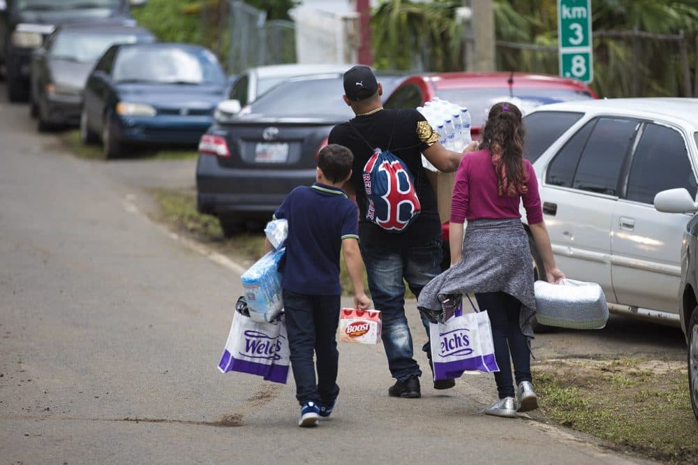 People walk down the road with bags of supplies collected at the Red Sox relief event. (Jesse Costa/WBUR)