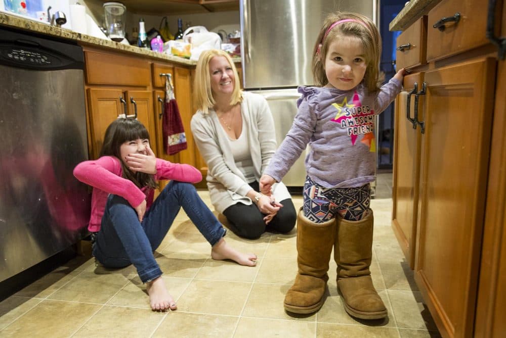 Rebecca tries on her mother's boots as her sister, Reagan, and mom, Beth Lacourse, look on. (Robin Lubbock/WBUR)