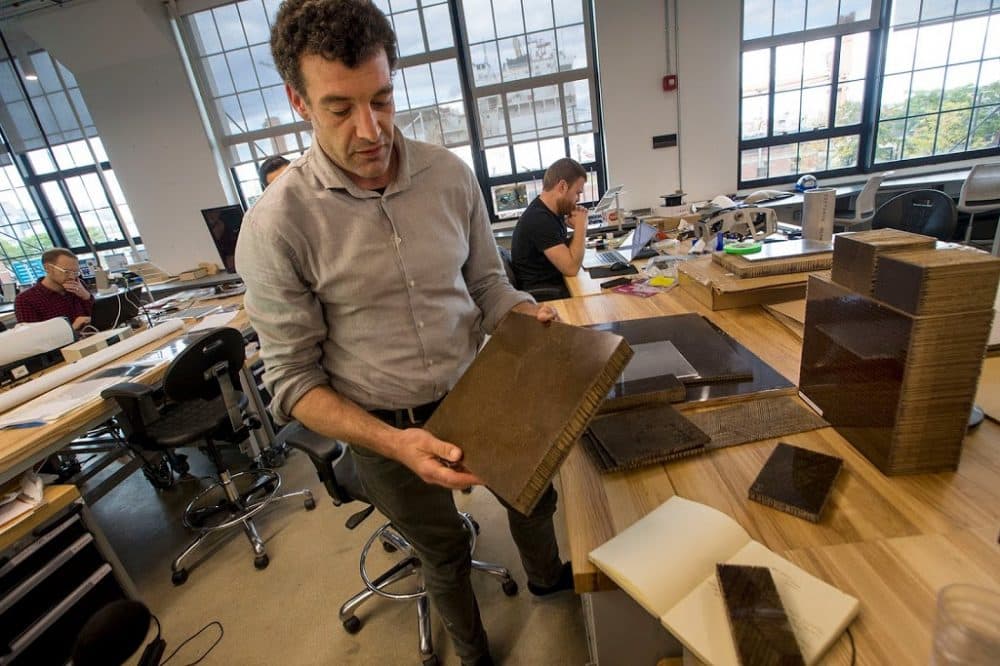 Seva Tsodokov of MetaComb holds a prefabricated building panel made from recycled waste stream corrugated cardboard. (Jesse Costa/WBUR)