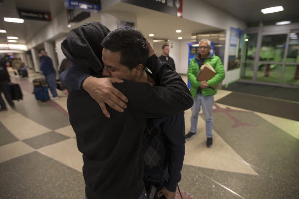 Isidro Macario, right, hugs his younger brother Erwin goodbye before being escorted by ICE officers to the boarding gate at Logan Airport. (Jesse Costa/WBUR)