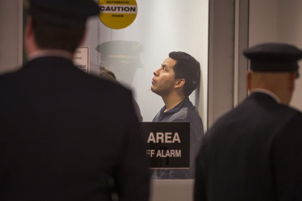 Isidro Macario waits at security as his travel documents are processed by ICE officers before boarding his flight. (Jesse Costa/WBUR)