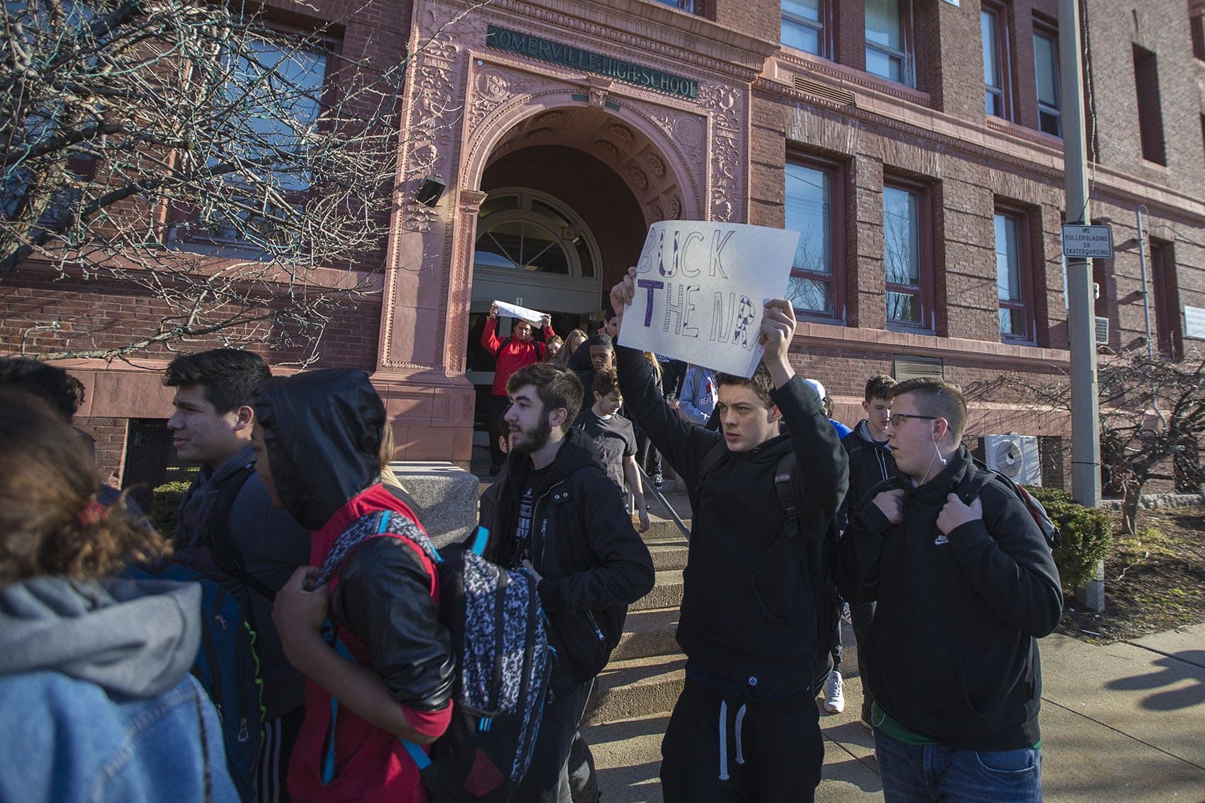 As Somerville High School students walk out of school to remember the lives lost in Parkland, Florida, Jack Torres holds a sign that reads "Buck the NRA." (Jesse Costa/WBUR)