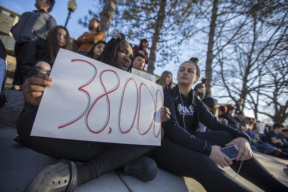 Students sit for 17 minutes on the sidewalk of Highland Avenue to remember the shooting victims from Parkland, Florida. (Jesse Costa/WBUR)