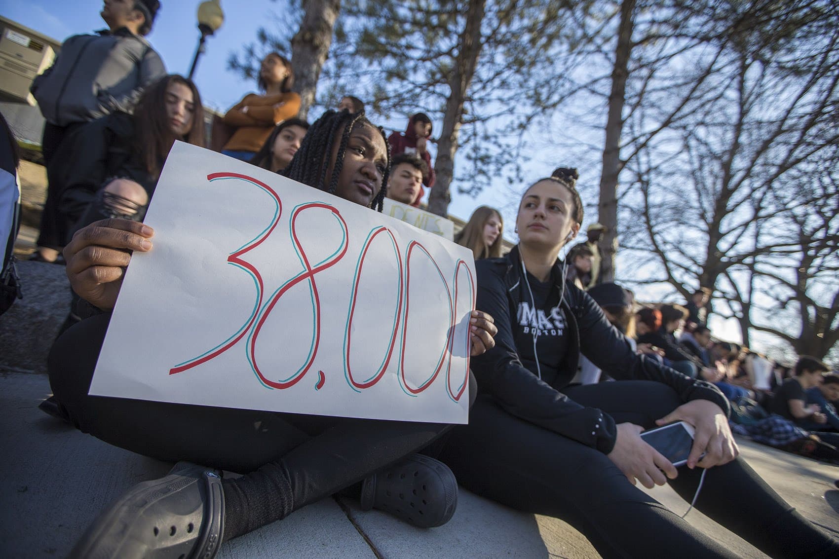 Students sit for 17 minutes on the sidewalk of Highland Avenue to remember the shooting victims from Parkland, Florida. (Jesse Costa/WBUR)