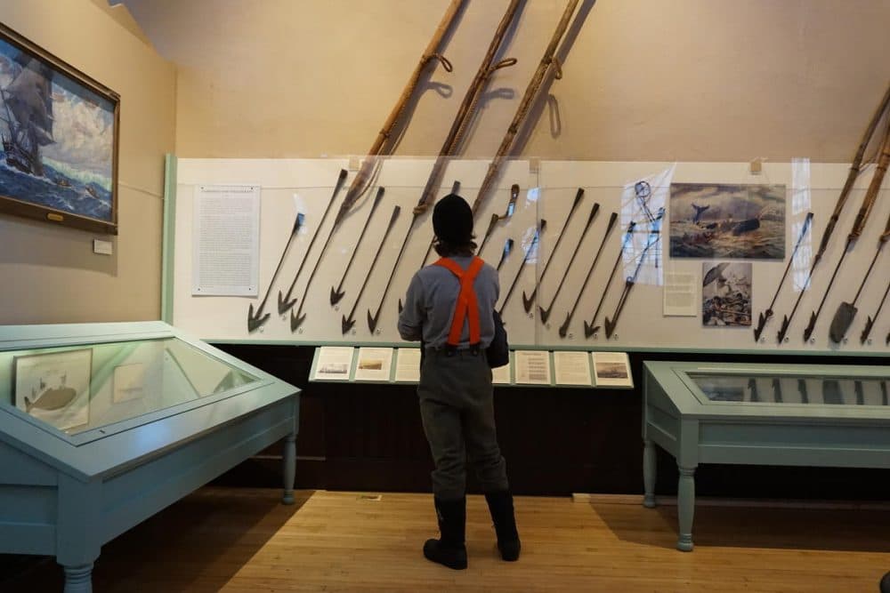 A man looks at harpoons used by whalers to kill the mammals in the water and bring them aboard their vessels at sea on display at the New Bedford Whaling Museum. (John Bender/RIPR)