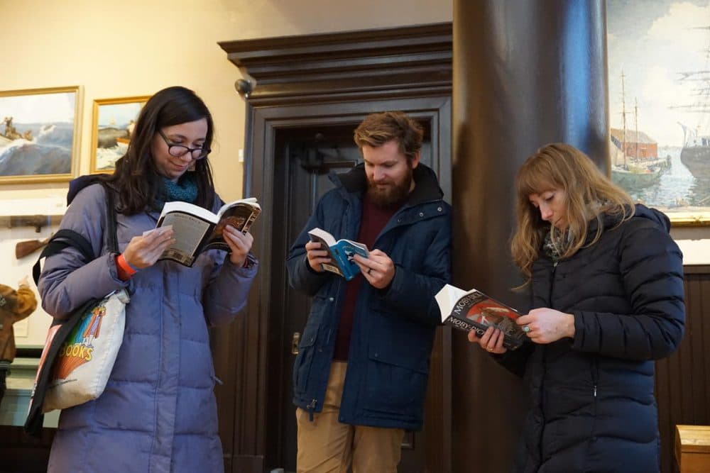 A trio of readers follow along during the public reading in their own copies of the book. (John Bender/RIPR)