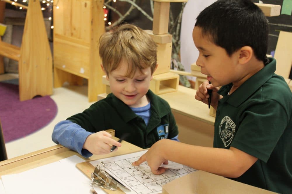 Kindergarten students Marco and Holden practice writing by labeling parts of a wolf they constructed in class. (Carrie Jung/WBUR)