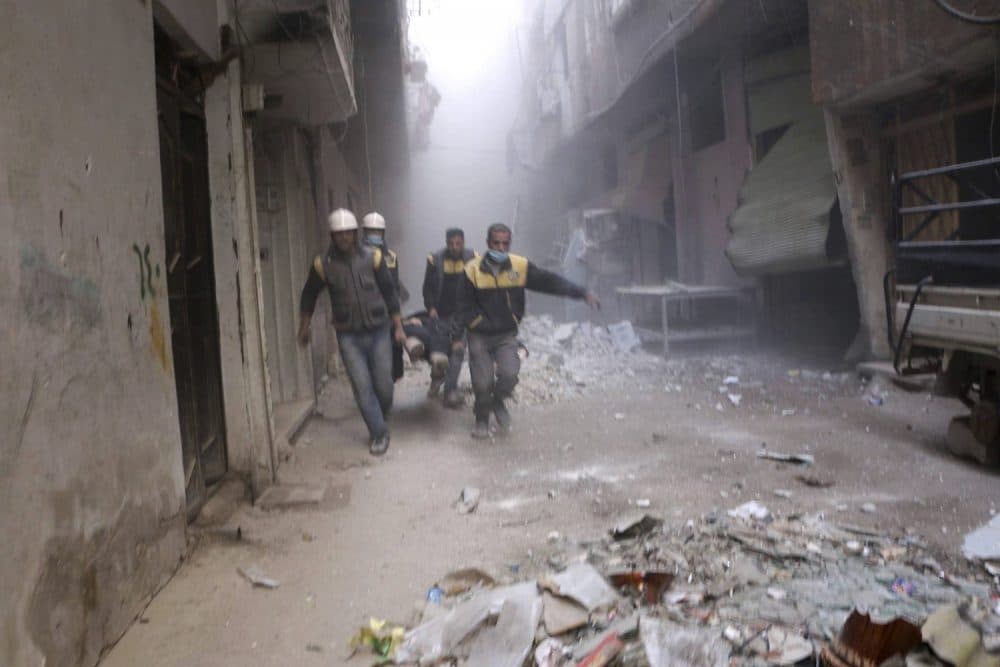 This photo released on Friday, Feb. 23, 2018 provided by the Syrian Civil Defense group known as the White Helmets, shows members of the Syrian Civil Defense group carrying a man who was wounded during airstrikes and shelling by Syrian government forces, in Ghouta, a suburb of Damascus, Syria. Syrian government warplanes supported by Russia continued their relentless bombardment of the rebel-controlled eastern suburbs of Damascus for a sixth day Friday, killing five people, opposition activists and a war monitor reported. The death toll from the past week climbed to more than 400. (Syrian Civil Defense White Helmets via AP)