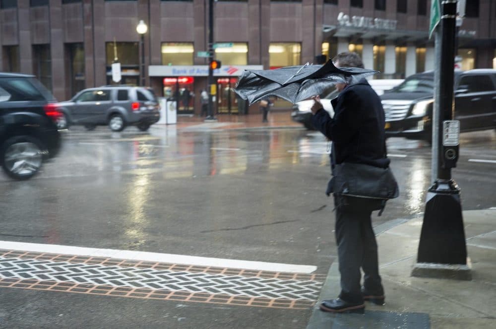 A gust of wind crumples this man's umbrella as he waits to cross State Street. (Robin Lubbock/WBUR)