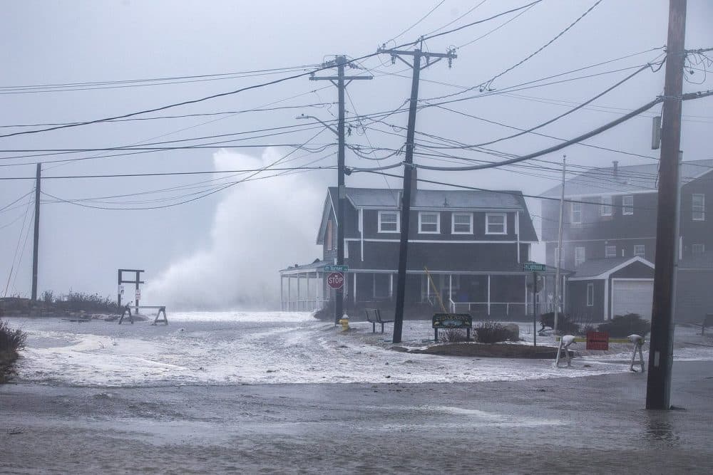 A wave crashes high above a house on Oceanside Ave in Scituate. (Jesse Costa/WBUR)