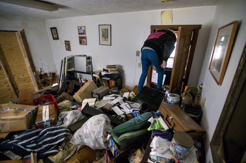 Taylor Fenton climbs over piles of debris on the first floor to get through to the next room. (Jesse Costa/WBUR)