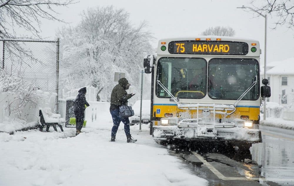 Bundled up against the snow, a woman boards a bus during the morning commute in Cambridge. (Robin Lubbock/WBUR)