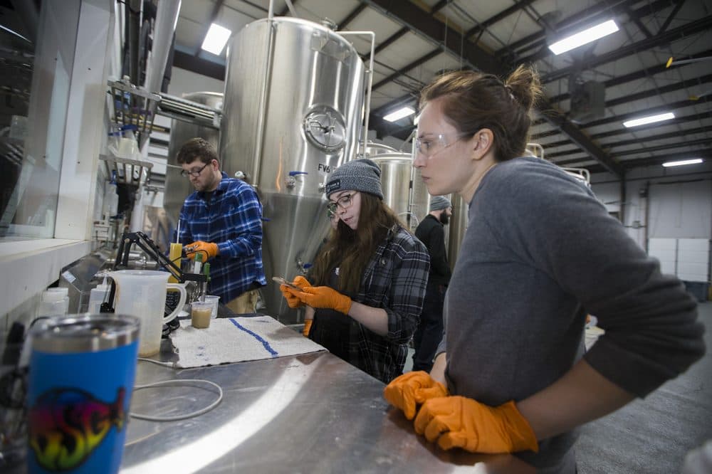 Katie Beaucage, center, and Lisa Small, right, check the ph level of the mash. (Jesse Costa/WBUR)