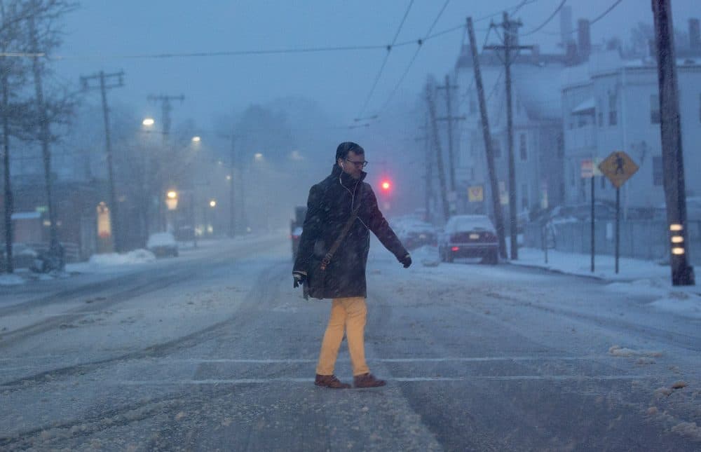 A man walks across Belmont Street in Cambridge as the snow begins to pick up in the early morning hours on Tuesday. (Jesse Costa/WBUR)