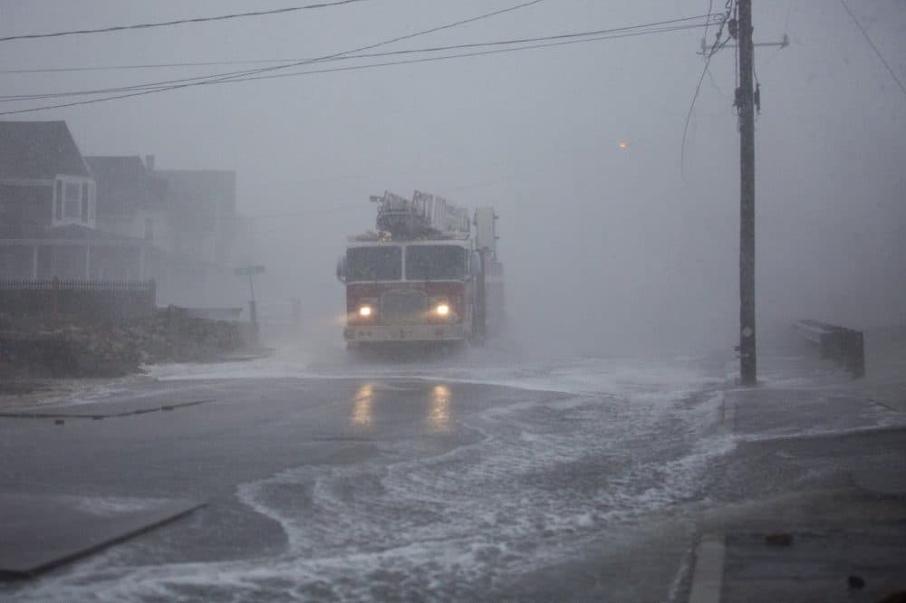 A Marshfield fire truck gets hit with wind and sea water from crashing waves on Ocean Street. (Jesse Costa/WBUR)