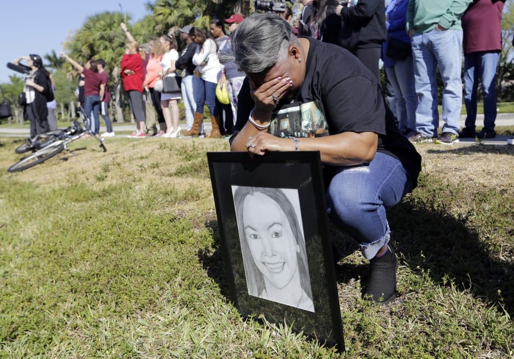Pat Gibson holds a drawing of Meadow Pollack, a victim of the Marjory Stoneman Douglas High School shooting, as she kneels outside of the school as part of a nationwide protest against gun violence on Wednesday in Parkland, Fla. (Lynne Sladky/AP)