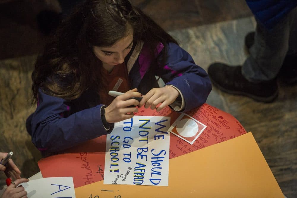 A student finishes creating a sign at a gathering at St. Paul's Cathedral before the march to the State House. (Jesse Costa/WBUR)
