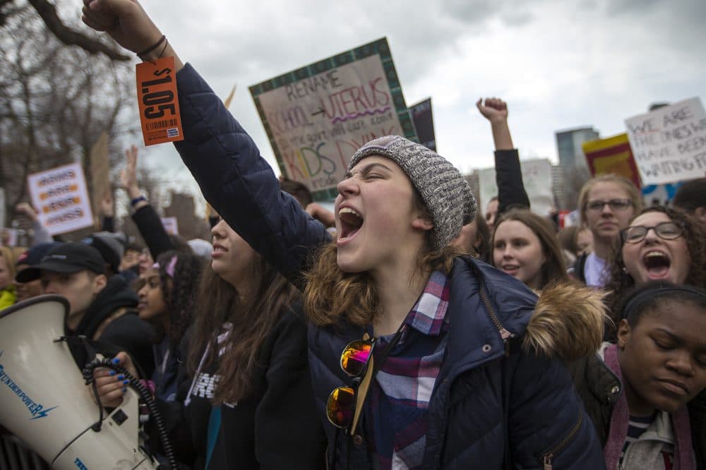 A protester with a $1.05 price tag on her wrist cheers during the rally. (Jesse Costa/WBUR)