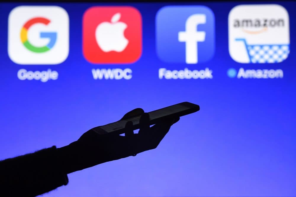 This photograph taken on Sept. 28, 2017, shows a smartphone being operated in front of logos for Google, Apple, Facebook and Amazon, in Hédé-Bazouges, western France. (Damien Meyer/AFP/Getty Images)