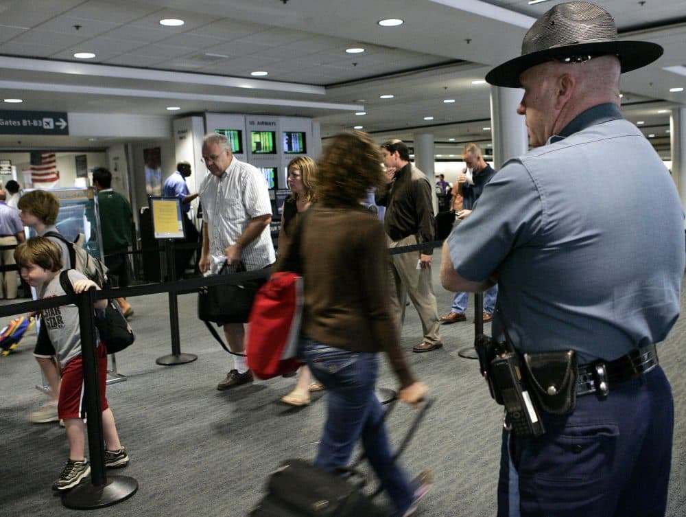 In this 2006 file photo, a Massachusetts state trooper keeps watch over travelers making their way through Logan International Airport in Boston. (Elise Amendola/AP)