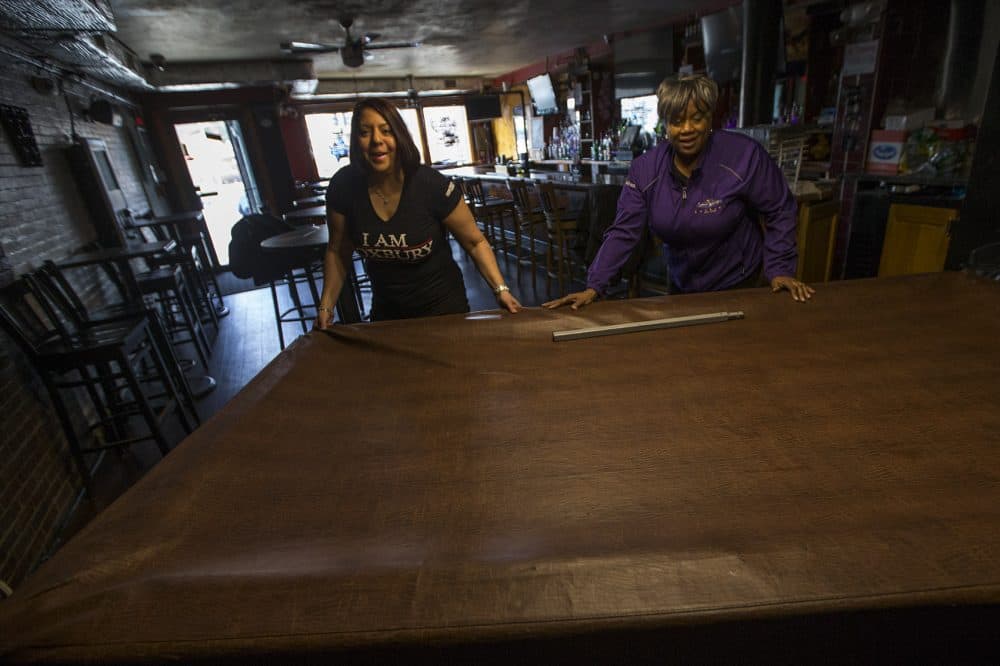 Mia McIlvany and Andrea Walker move the pool table out of the way to make room for that evening's entertainment. (Jesse Costa/WBUR)