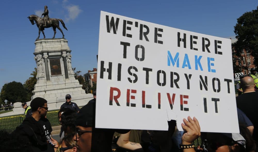 Protesters hold signs in front of the statue of Confederate General Robert E. Lee on Monument Avenue in Richmond, Va., Saturday, Sept. 16, 2017. (Steve Helber/AP)