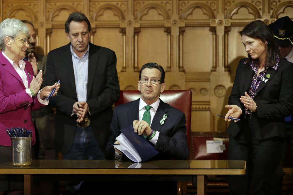 Connecticut Gov. Dannel Malloy, center, completes signing legislation that includes new restrictions on weapons and large capacity ammunition magazines, on April 4, 2013. Malloy is applauded by relatives of victims of the Sandy Hook shooting. (Steven Senne/AP)