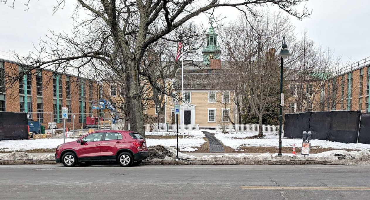 The renaming of a school in Brookline brings up a bigger question, writes Jessica Ullian. Why are certain figures remembered while others are pushed aside? In this photo: The small yellow structure is the original home of Edward Devotion, circa 1740. The darker yellow structure is the original elementary school. The red-brick structure is the new construction. (Courtesy)