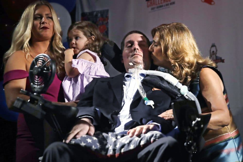 In this Sept. 18, 2017, photo, Pete Frates, who was the inspiration of the Ice Bucket Challenge, is kissed by his mother Nancy while appearing with his wife Julie and daughter Lucy at Fenway Park in Boston. The challenge raised millions of dollars for research on Lou Gehrig's disease. He died in late 2019 at age 34. (AP Photo/Charles Krupa)