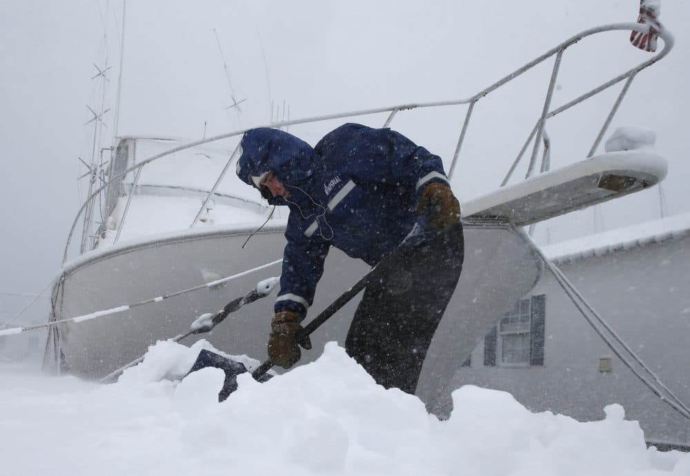 Gray Harrington clears snow from a dock at the Boston Harbor Shipyard and Marina in Boston. (Michael Dwyer/AP)