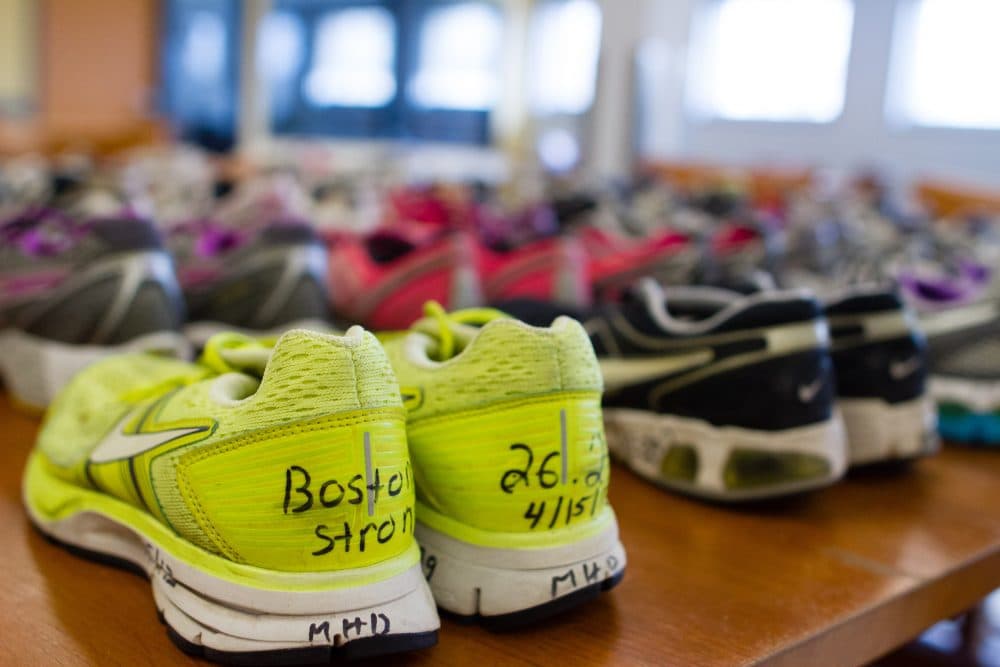 Shoes left at a pop-memorial following the 2013 Boston Marathon bombing are arranged on a table in the Boston City Archives. The sneakers are on display in Attleboro. (Elizabeth Gillis/WBUR)