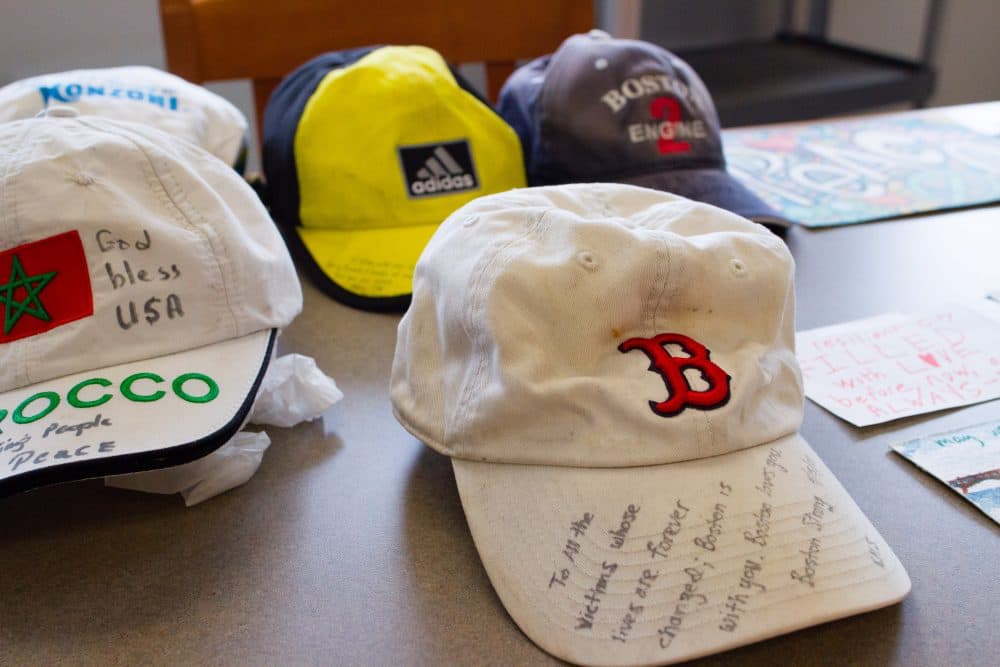 Hats and signs that were left at the pop-up memorial for the Boston Marathon bombing are arranged on tables at the Boston City Archives. (Elizabeth Gillis/WBUR)