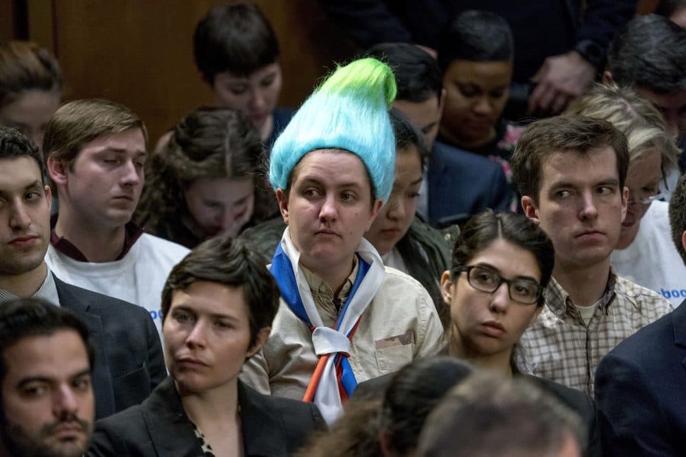 Ian Madrigal seen wearing a blue and green pointy wig, aiming to look like a Russian troll, as Facebook CEO Mark Zuckerberg testifies before a joint hearing of the Commerce and Judiciary Committees on Capitol Hill in 2018. (Andrew Harnik/AP)