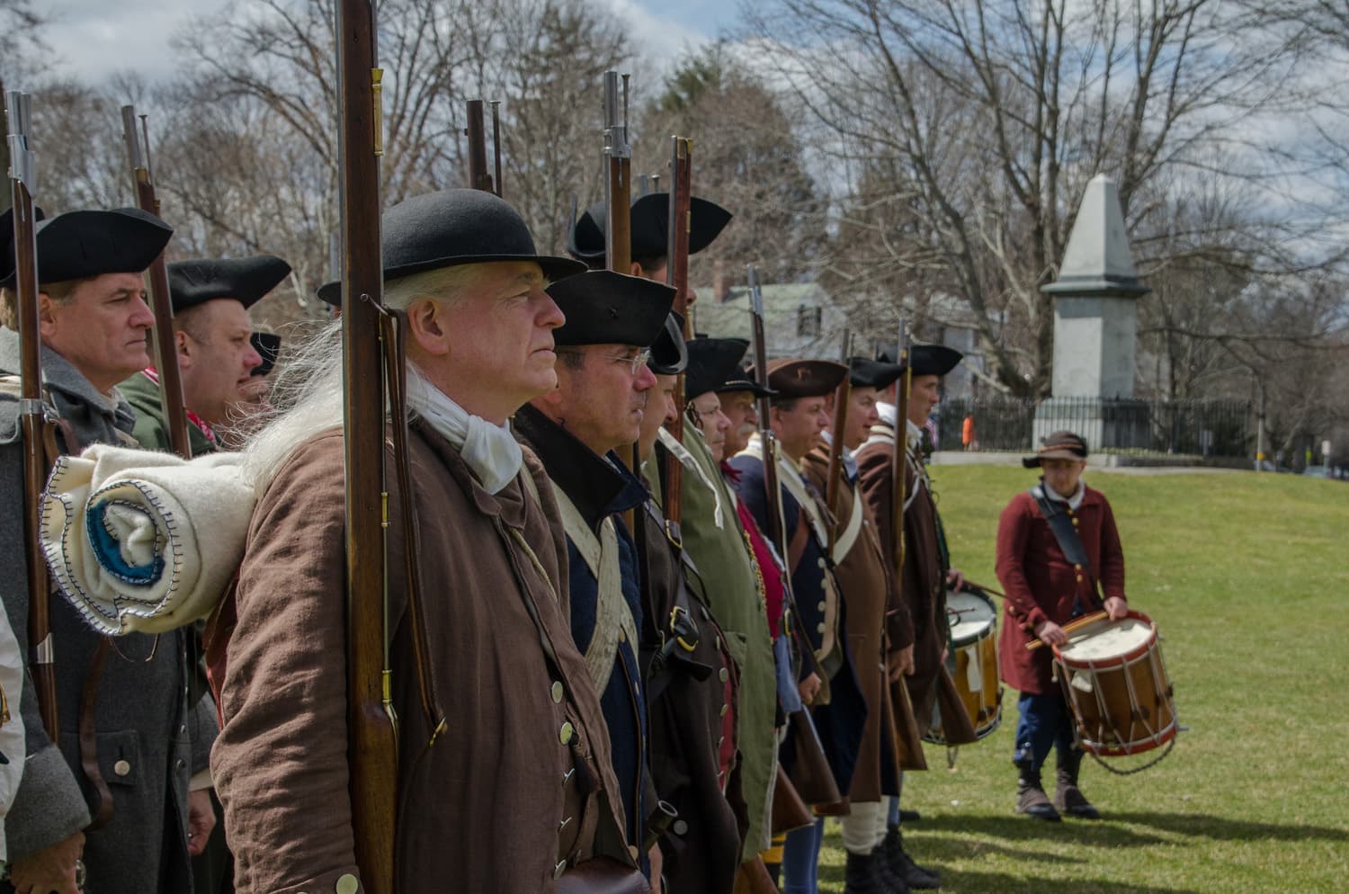 The 2018 Lexington Minute Men assemble near the monument commemorating the men who died on the green in 1775. (Sharon Brody/WBUR)
