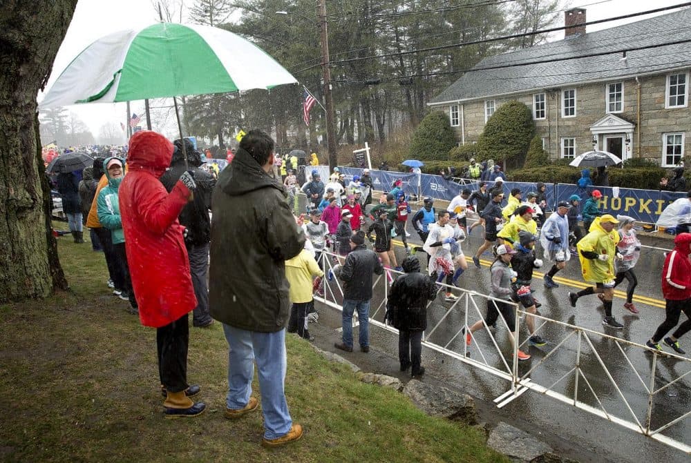 Marathon supporters shelter under an umbrella as runners leave Hopkinton. (Robin Lubbock/WBUR)