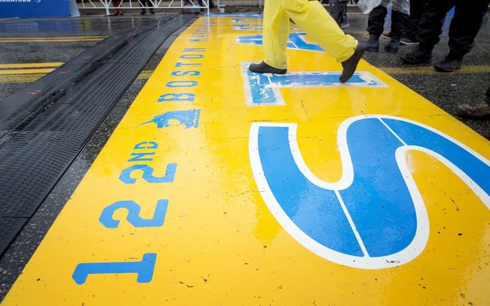 Early on, a man walks across the start line in his rain gear. (Robin Lubbock/WBUR)