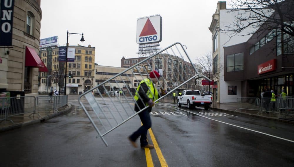 Workers set up barriers along Brookline Avenue in Kenmore Square. (Jesse Costa/WBUR)
